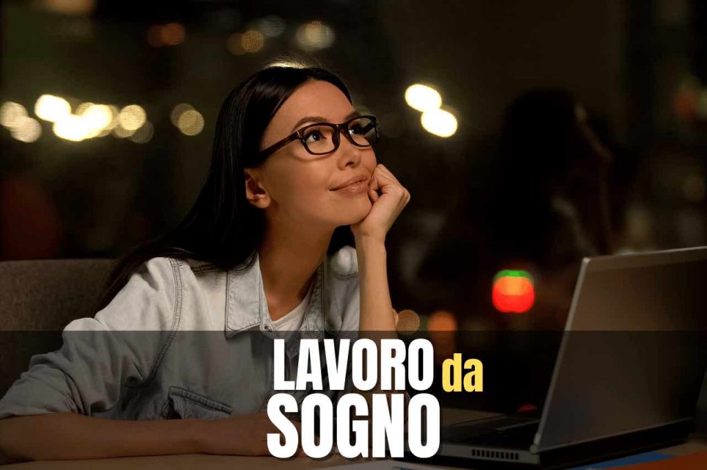 Ragazza seduta alla scrivania e al pc, con sguardo sognante