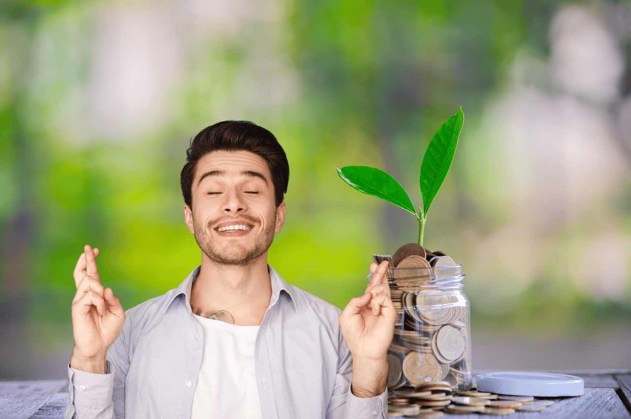 Uomo con dita incrociate, barattolo con monete alle spalle