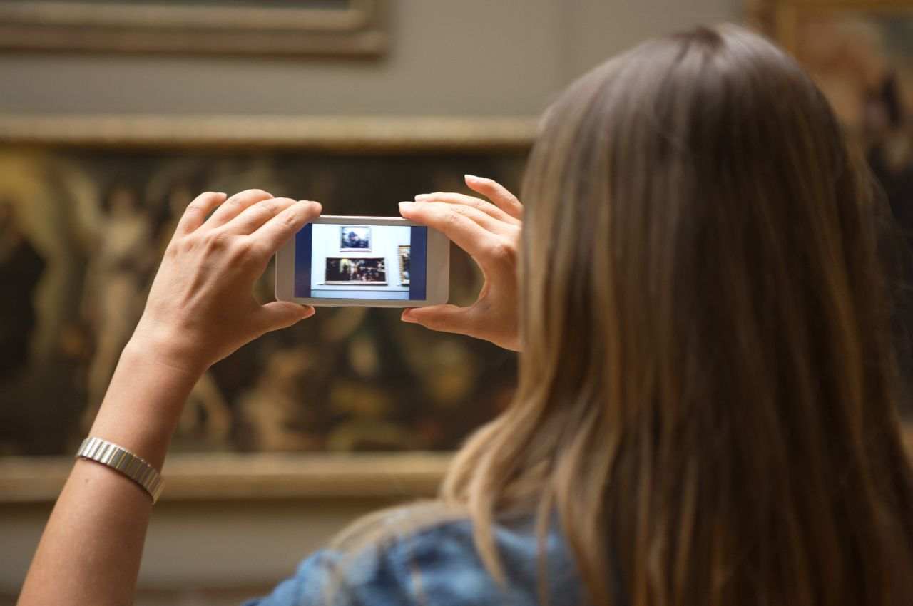 ragazza che fotografa un dipinto in un museo