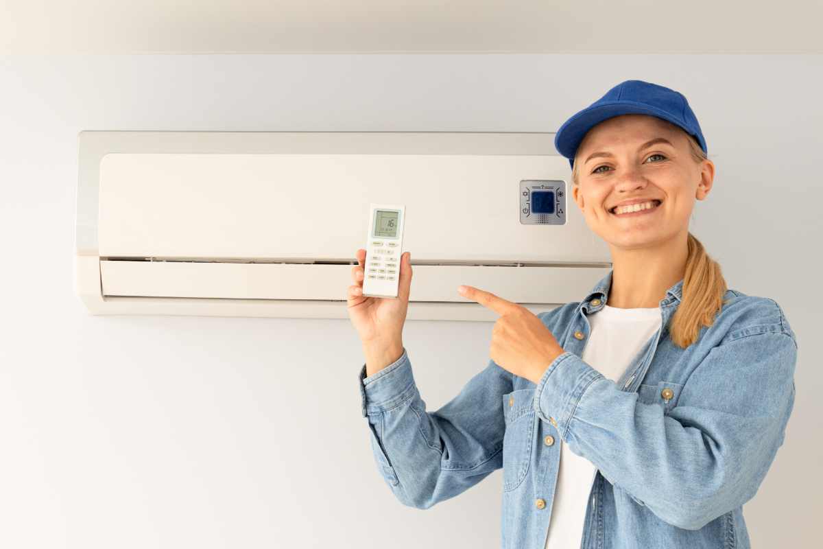 tecnico davanti al condizionatore mostra il telecomando sorridendo